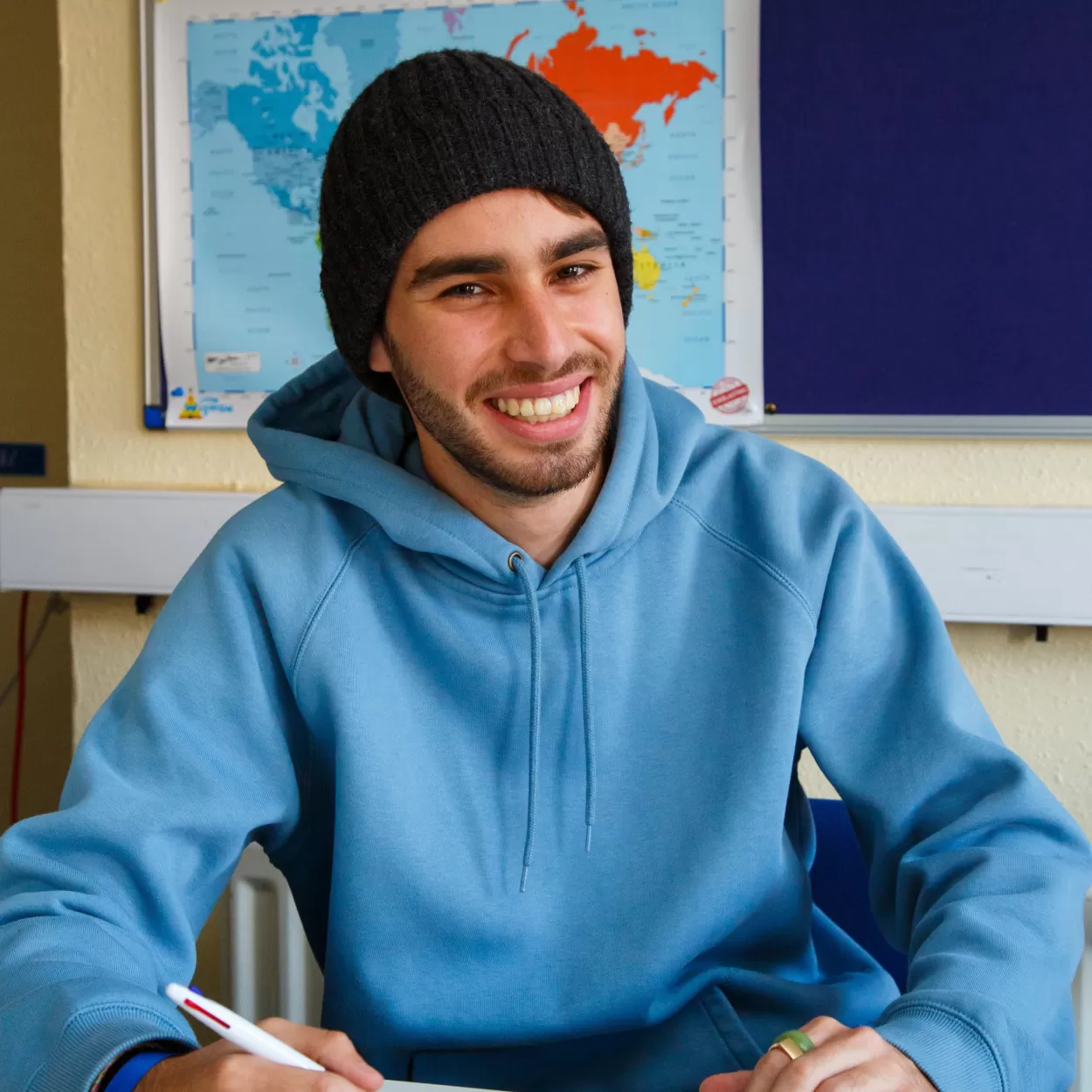 A photo of Mathieu Galliano from France studying at ELC Chester in January 2023. He's wearing a pale blue hoodie and a black beanie hat, and he's smiling at the camera.