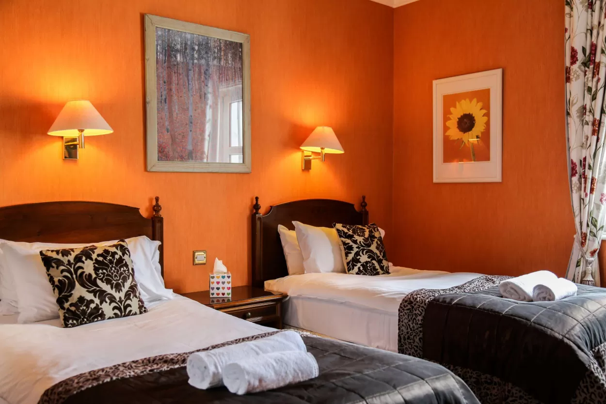 This is a striking image of a twin bedroom at the Wilmington hotel in Eastbourne. Striking because the wall behind the beds is bright orange in colour which contrasts nicely with the dark wood of the beds and the crisp white sheets and towels.