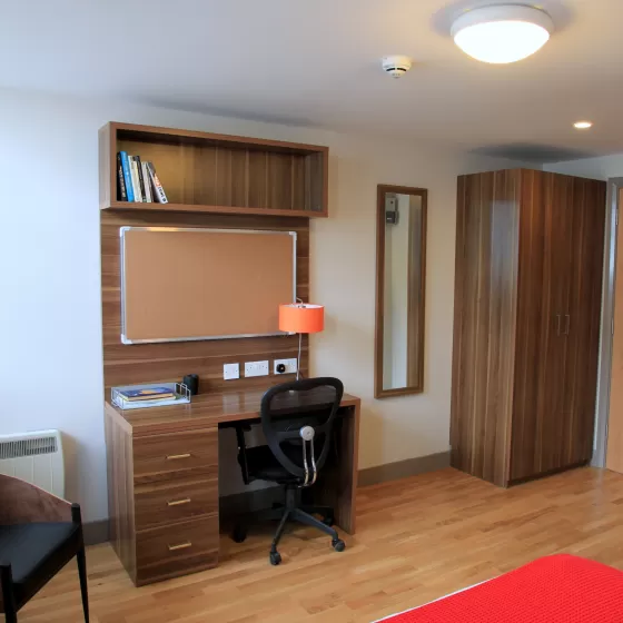 A typical study room in the Britannia residence in Brighton which ELC English language centre offers to its students. The floor is an oak-coloured laminate with darker wood wardrobe and desk. It looks clean and stylish.