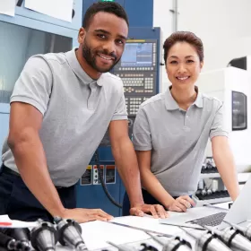 This is a library shot of a man and woman in matching pale grey polo shirts standing in what looks like a laboratory or other technical facility. We're using this image to highlight ELC's English for engineers programme in Brighton.